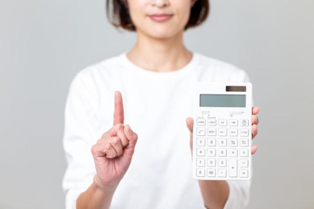 人差し指を立てて電卓を持つ女性