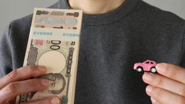 ミニカーと現金を持つ人