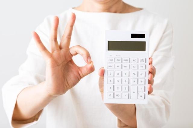 電卓を手にOKサインを出す女性