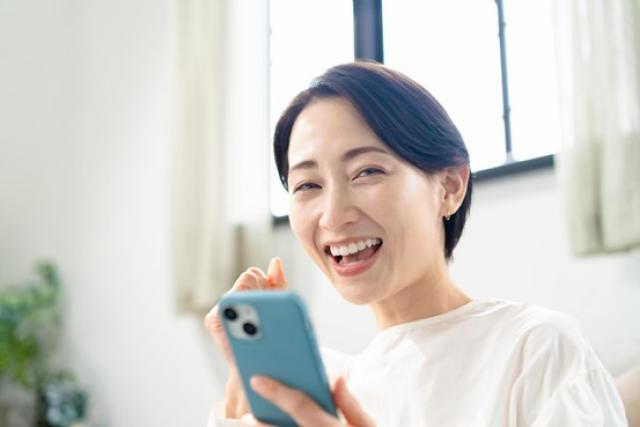 スマホを手に喜ぶ女性