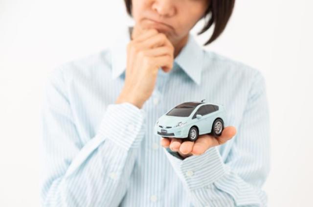 ミニカーを手に考える女性