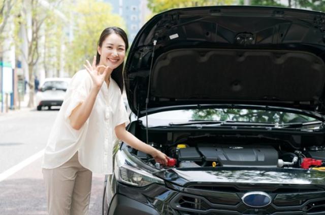 車のボンネットを開けてOKサインを出す女性