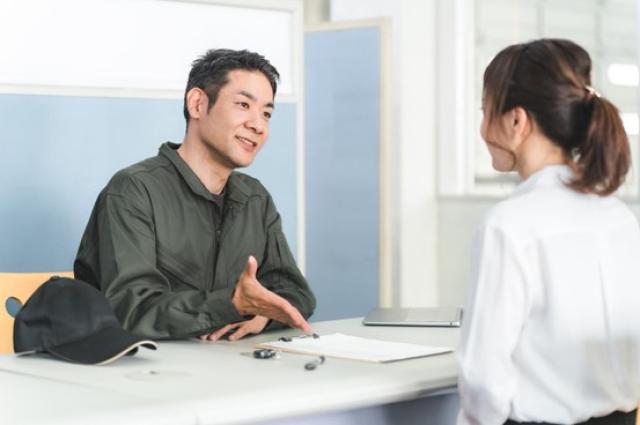 受付で説明する整備士の男性