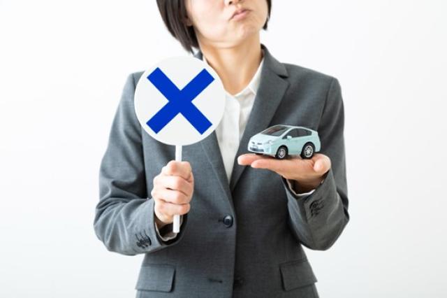 ミニカーと×のマークを持つ女性