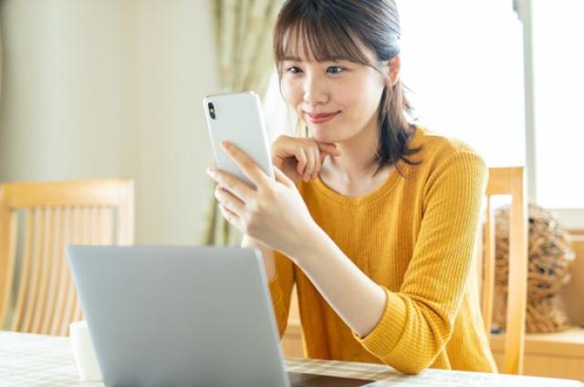 パソコンとスマホで手続きをする女性