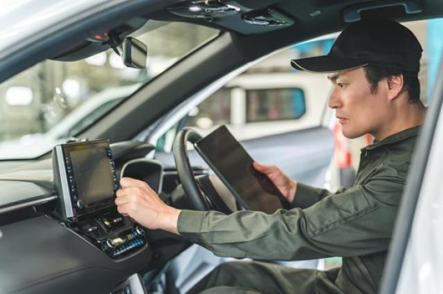 車内でタブレット端末を使う自動車整備士の男性