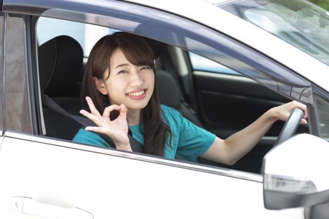 運転席でOKサインをする女性