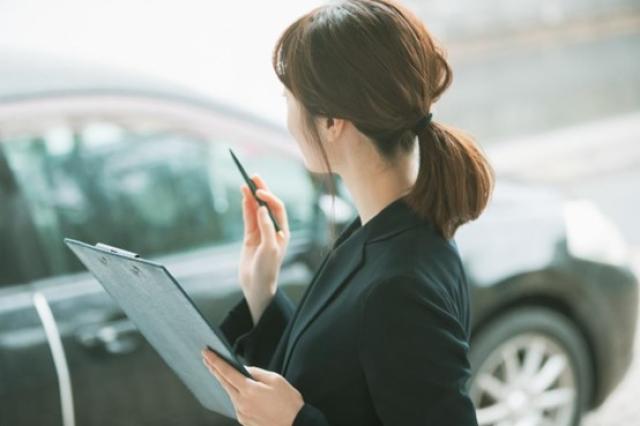 車をチェックするスーツの女性