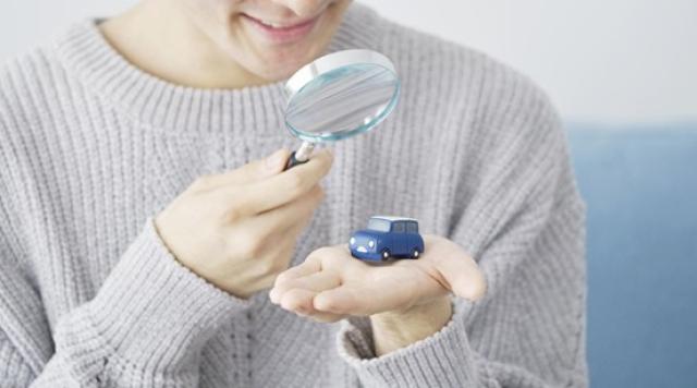 ミニカーと虫メガネを使う男性