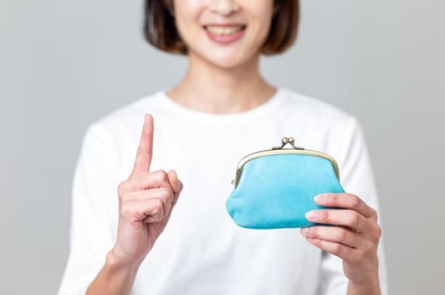 青いがま口財布を持って人差し指を立てる女性