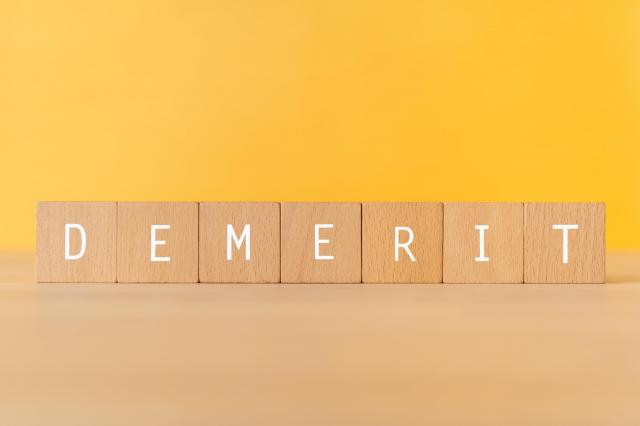 アルファベットが書かれたブロックで「DEMERIT」と表現
