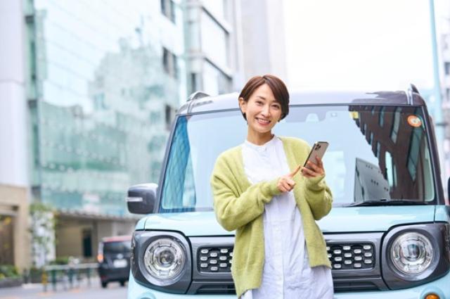 車の前でスマホを触る女性