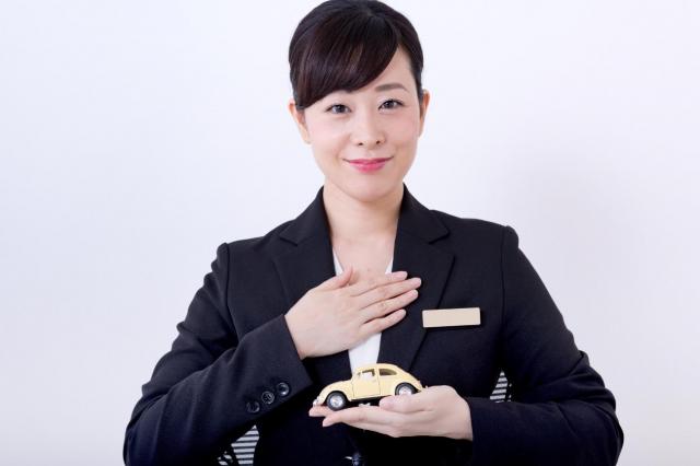 ミニカーを持ち、胸に手を当てたビジネスパーソン