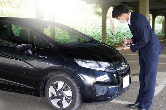 車をチェックするビジネスパーソン