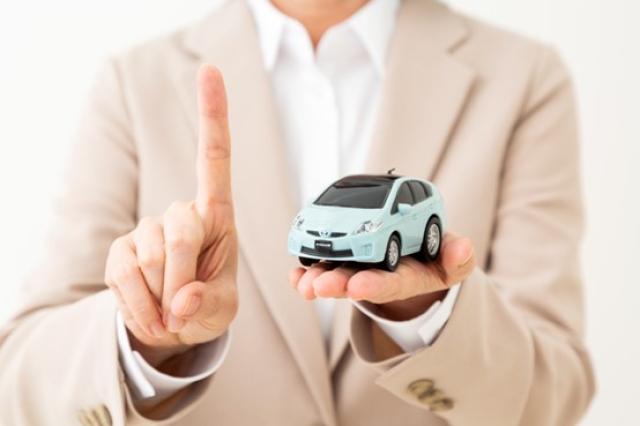 ミニカーを持ちつつ、人さし指を立てた人