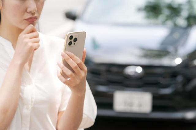 スマホを手に考える女性