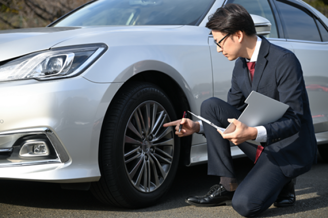 車の傷を確認するビジネスマン