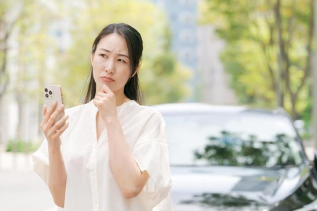 携帯を持って考え込む女性