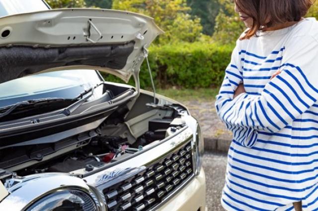 ボンネットを開けて腕を組む女性