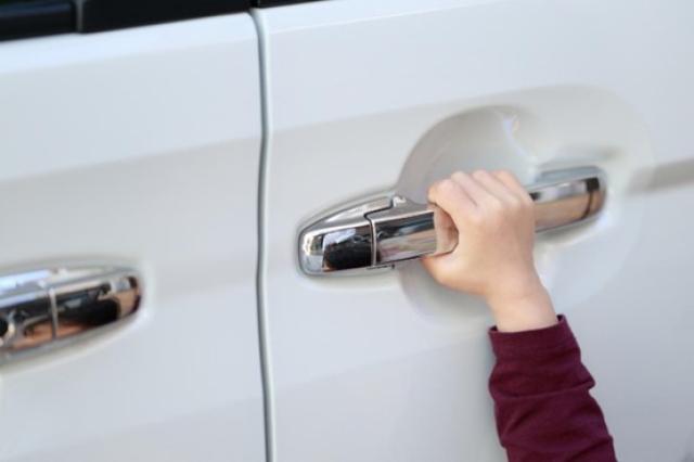 スライドドアのドアノブをつかむ子どもの手