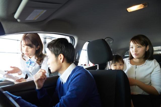 ショールームで家族連れに車を紹介する様子
