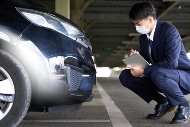 自動車をチェックするマスク姿の男性