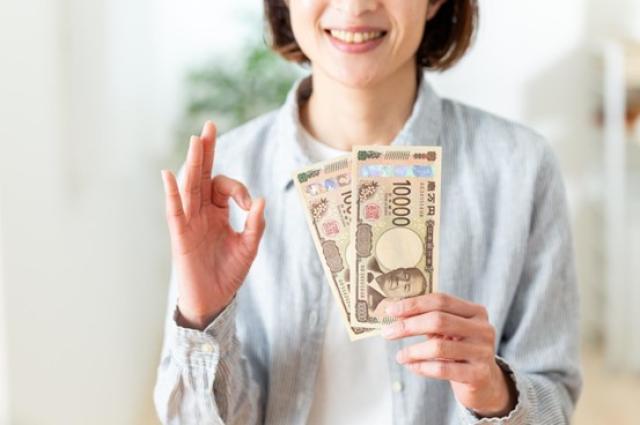 現金を持ってOKサインを出す女性