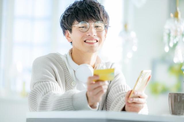クレジットカードを持つ笑顔の男性