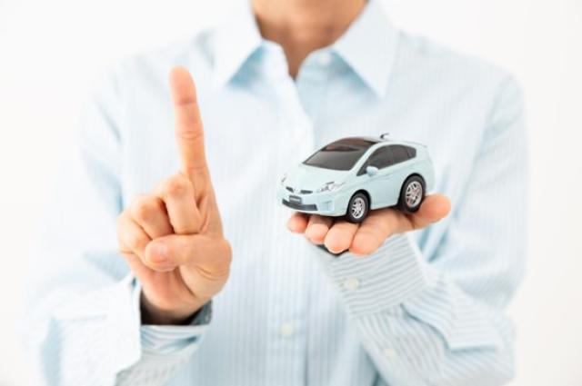 ミニカーと人差し指を立てる男性