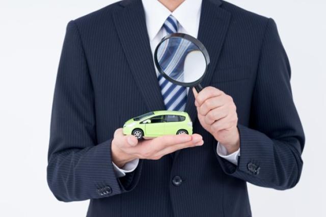 ミニカーと虫メガネを持つ男性