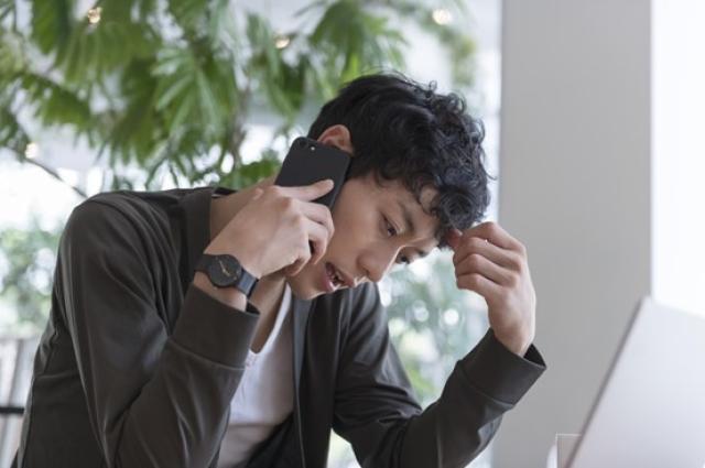 困り顔で電話する男性