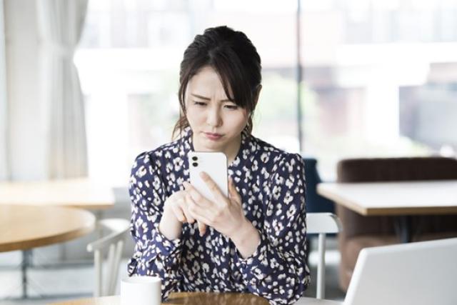 スマホを見て悩む女性