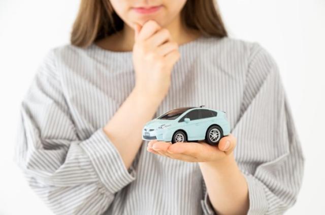 ミニカーを手に考える女性