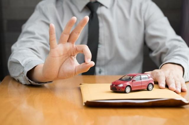 ミニカーと書類、OKサインをする男性