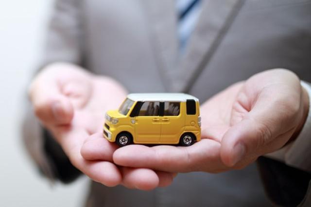 軽自動車のミニカーを持つ営業マン