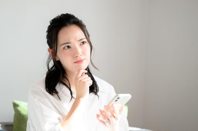 スマホを片手に悩む女性