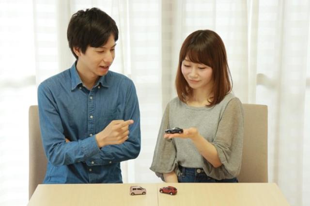 ミニカーを手に乗せて話す男女