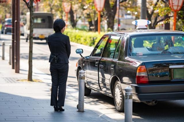 タクシーの横に立つ女性