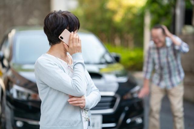 車の横で困る男性と電話をかける女性