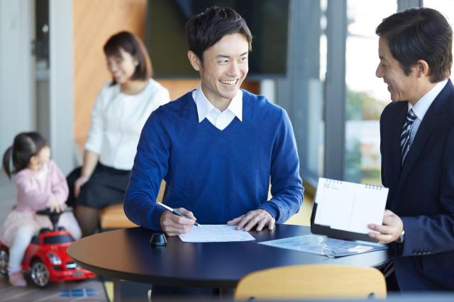自動車販売店で手続きをする男性