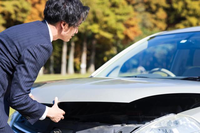 車のボンネットを開ける男性