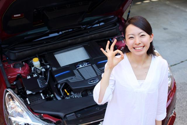 車のボンネットを開きOKサインを出す女性