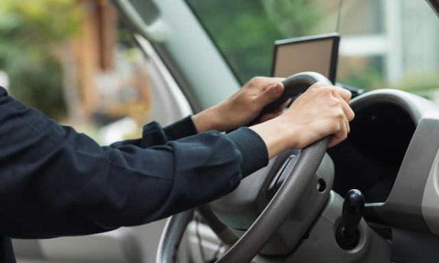 アイドリング中の車のハンドルを握るドライバー