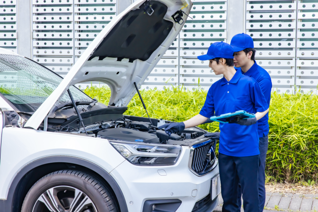 自動車のエンジンルームを点検する作業員