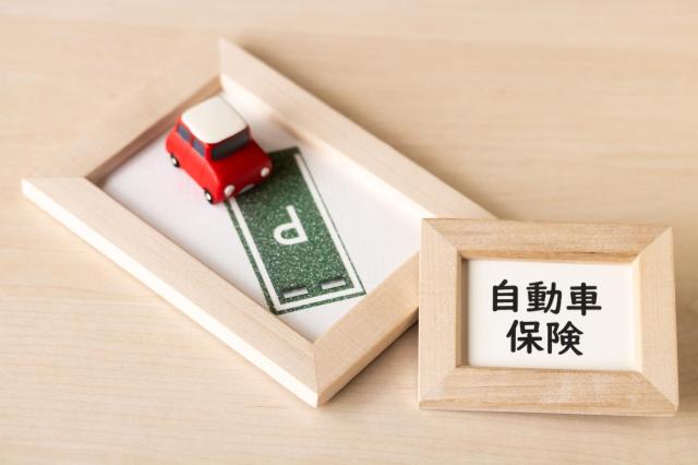 自動車保険と書かれたフレームと赤いミニカー