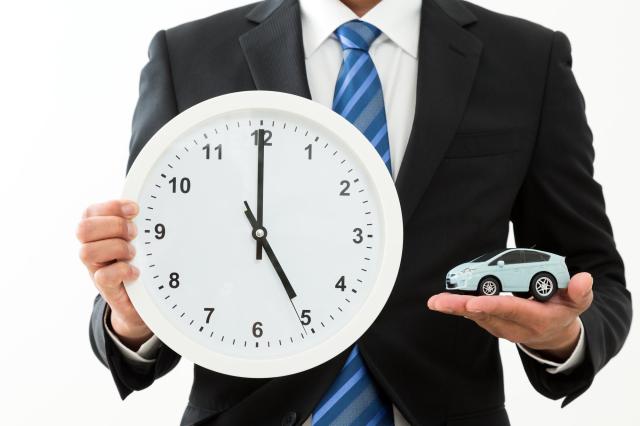 時計とミニカーを持ったスーツの男性