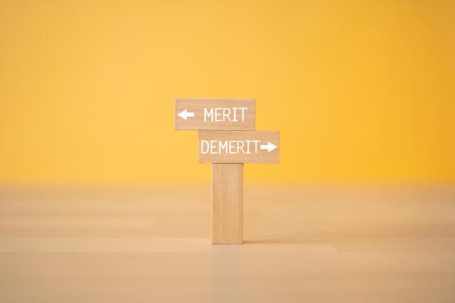 メリット・デメリットと書かれた木製の看板