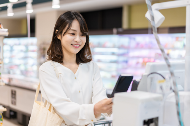 レジで電子マネー決済をする女性