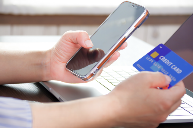 スマホとクレジットカードを持つ女性