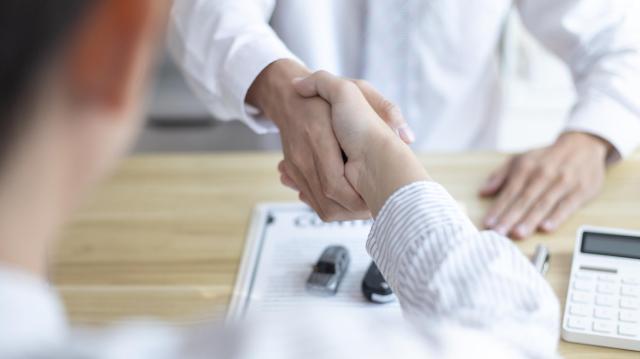 ミニカーと書面の上で握手をする人